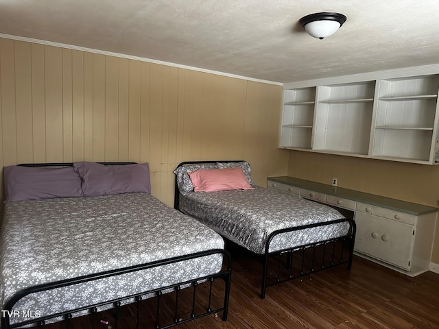 bedroom featuring wood walls, dark hardwood / wood-style flooring, ornamental molding, and a textured ceiling