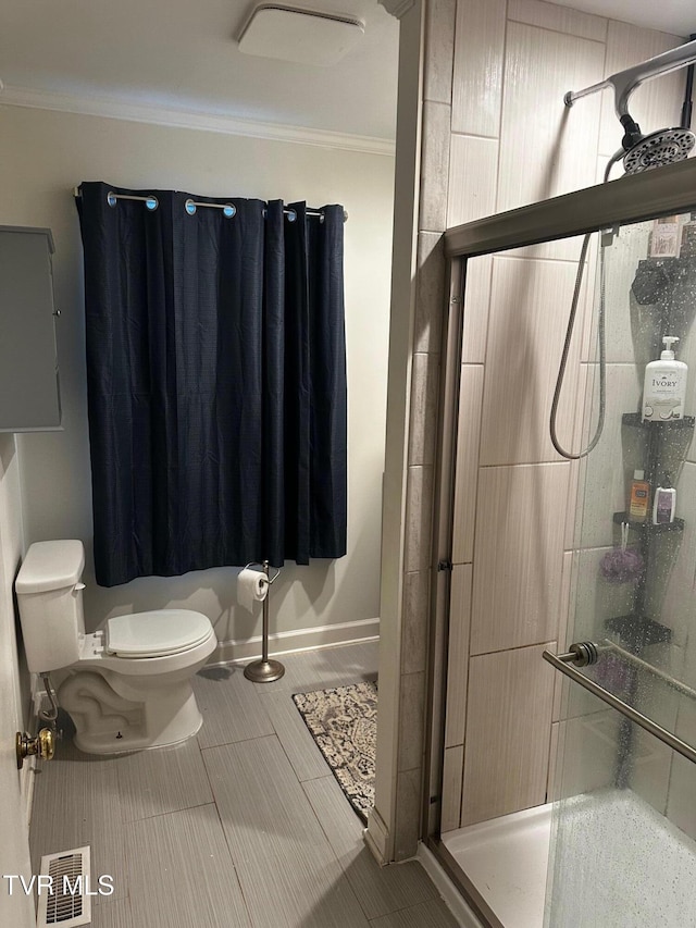 bathroom featuring tile patterned floors, toilet, a shower with shower door, and crown molding