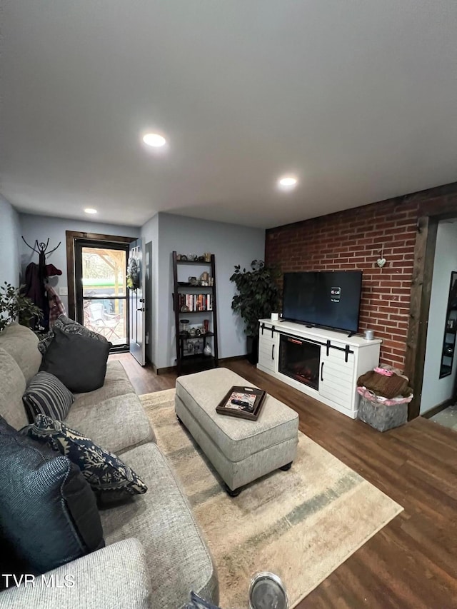 living room featuring wood-type flooring and a brick fireplace