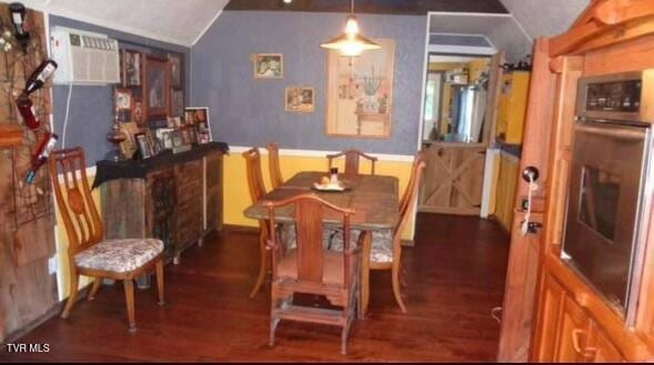 dining space with dark hardwood / wood-style floors, an AC wall unit, and vaulted ceiling