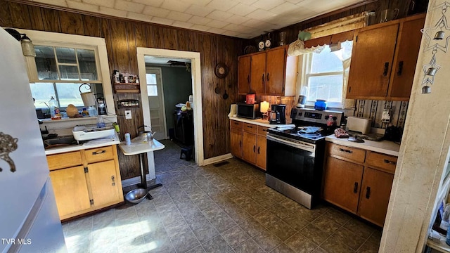 kitchen with a healthy amount of sunlight, stainless steel range with electric cooktop, and wood walls