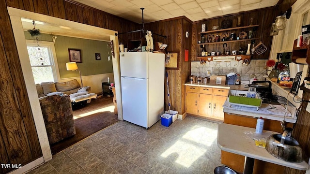 kitchen with decorative light fixtures, white fridge, and wooden walls