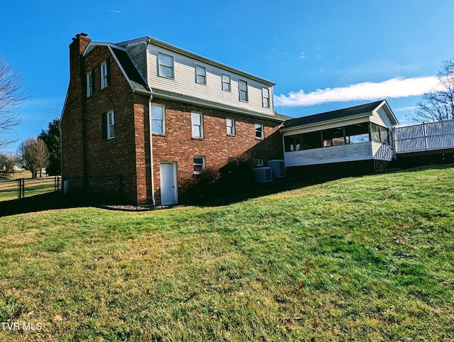 back of house featuring a lawn, central air condition unit, and a sunroom