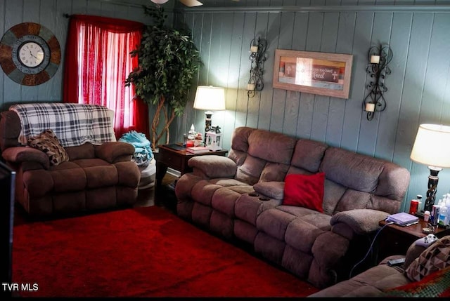 living room with ceiling fan and wood walls