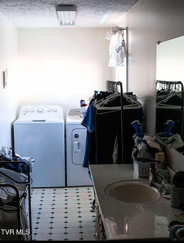 washroom with sink, a textured ceiling, and washing machine and clothes dryer