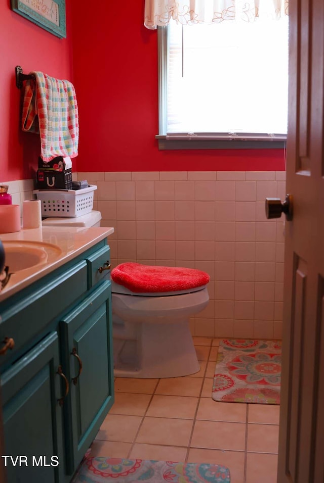 bathroom featuring toilet, vanity, tile patterned floors, and tile walls