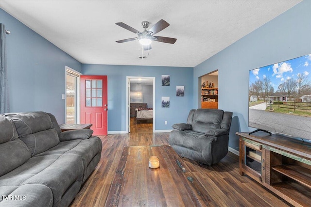 living room featuring dark hardwood / wood-style floors, ceiling fan, and a textured ceiling