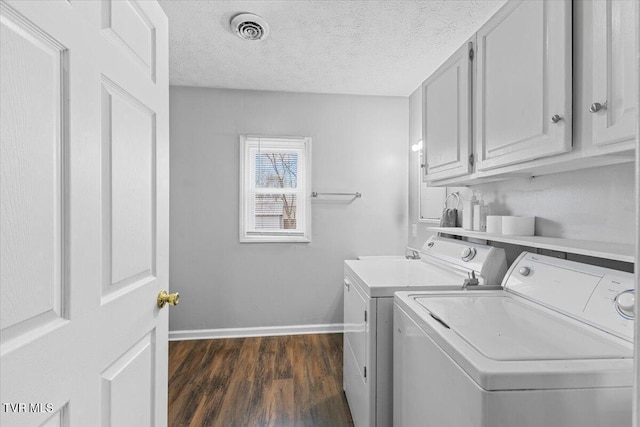 laundry room featuring dark hardwood / wood-style flooring, cabinets, a textured ceiling, and washing machine and dryer