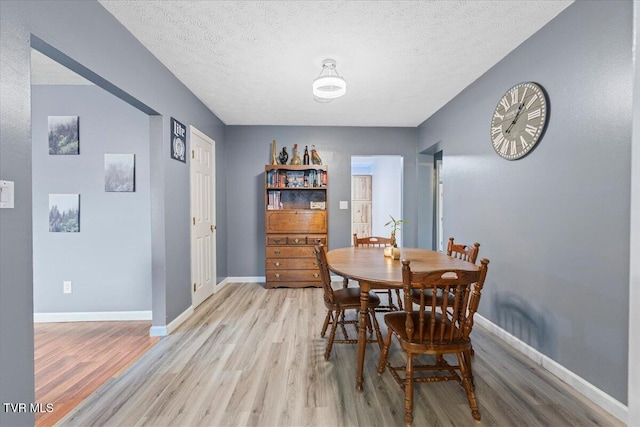 dining room with a textured ceiling and light wood-type flooring