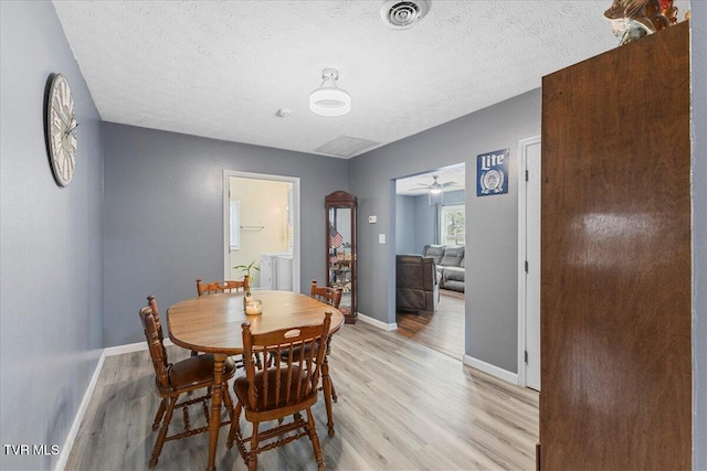 dining space featuring a textured ceiling, separate washer and dryer, and light hardwood / wood-style flooring