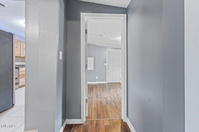 hallway with wood-type flooring, a textured ceiling, and lofted ceiling