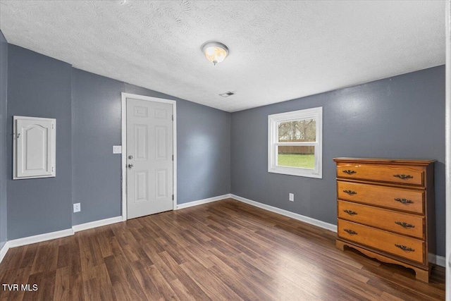 spare room featuring lofted ceiling, a textured ceiling, and dark wood-type flooring