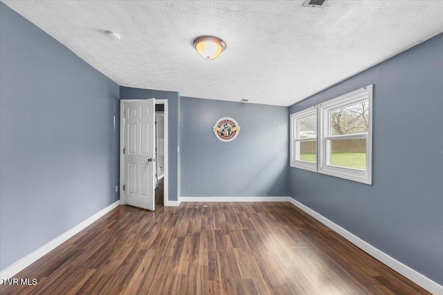 spare room with a textured ceiling and dark hardwood / wood-style floors