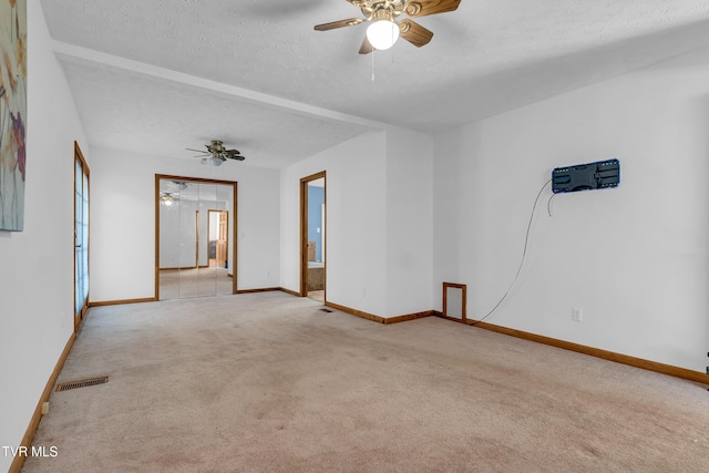 carpeted empty room featuring ceiling fan and a textured ceiling