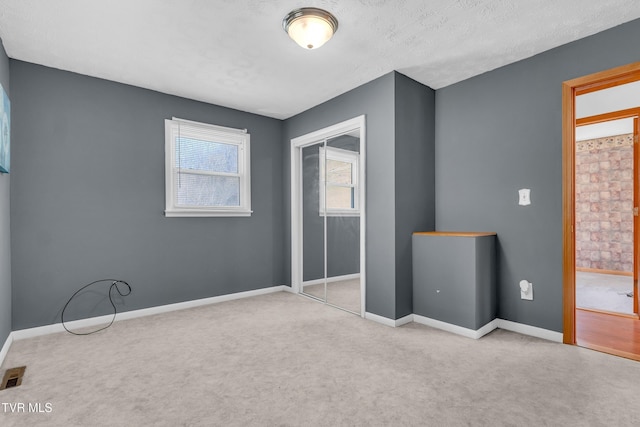 unfurnished bedroom with a textured ceiling, light colored carpet, and a closet