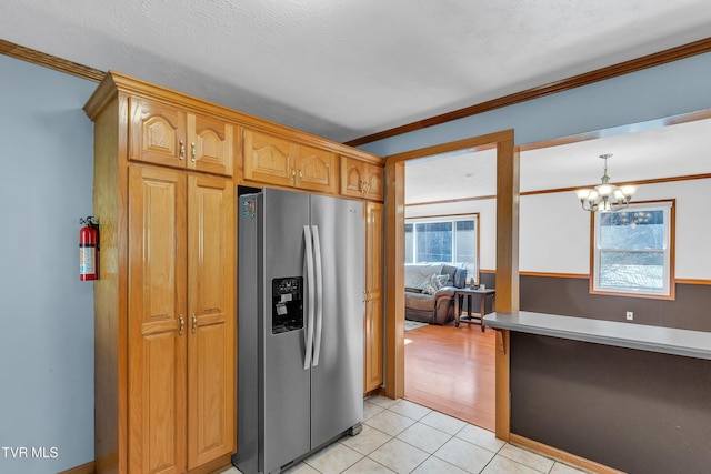 kitchen featuring crown molding, stainless steel refrigerator with ice dispenser, hanging light fixtures, light tile patterned floors, and a notable chandelier