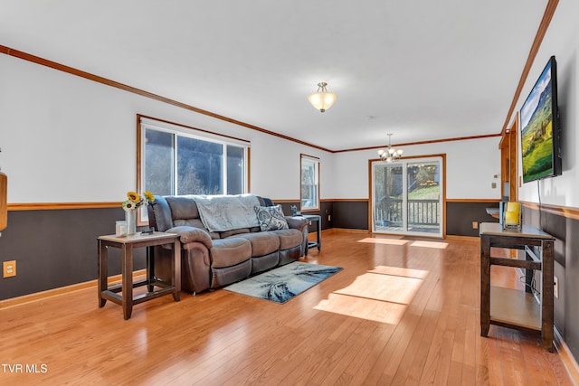 living room with a notable chandelier, light hardwood / wood-style floors, and crown molding