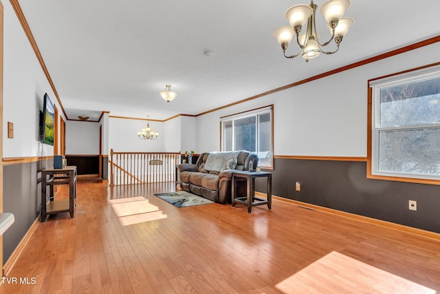 living room with wood-type flooring, crown molding, and an inviting chandelier