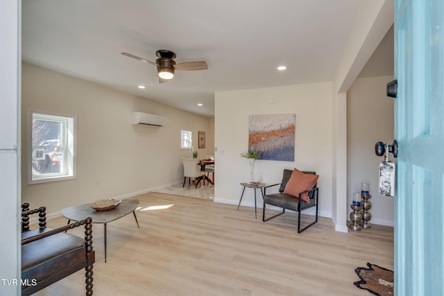 living area featuring ceiling fan, a wall unit AC, and light wood-type flooring