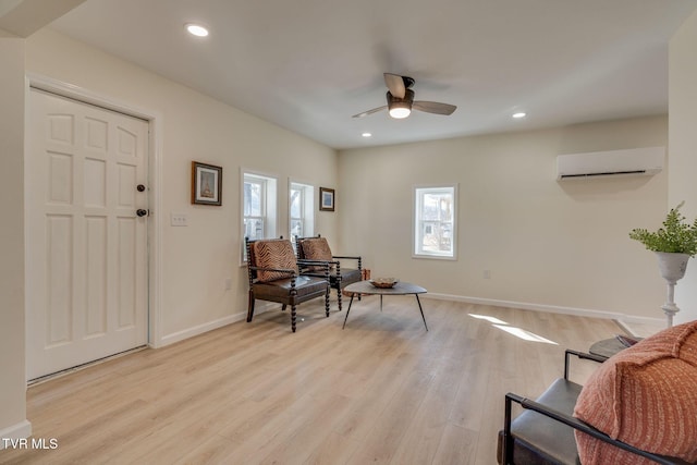 living area featuring ceiling fan, a wall mounted air conditioner, and light wood-type flooring