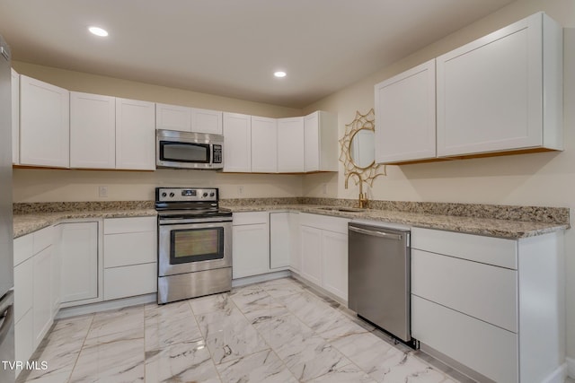 kitchen with white cabinetry, appliances with stainless steel finishes, sink, and light stone counters