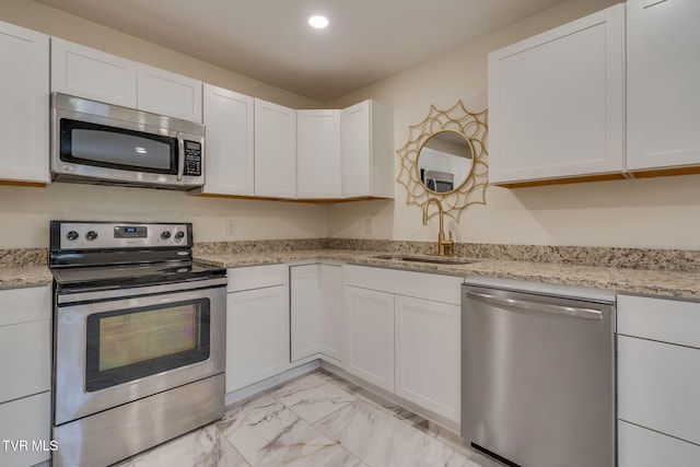 kitchen featuring light stone counters, appliances with stainless steel finishes, sink, and white cabinets