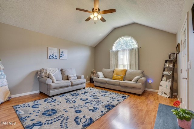 living room featuring vaulted ceiling, wood-type flooring, ceiling fan, and a textured ceiling