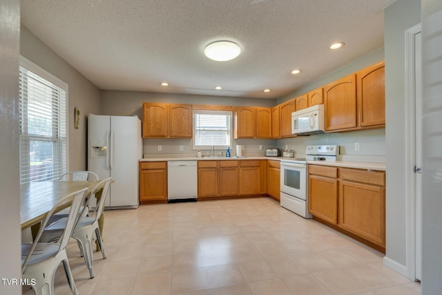 kitchen with sink, a textured ceiling, and white appliances