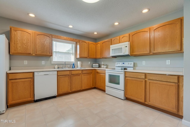 kitchen featuring white appliances, sink, and a textured ceiling