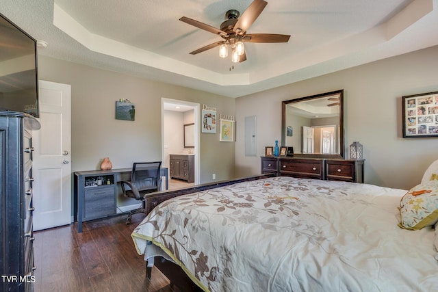 bedroom featuring ceiling fan, dark hardwood / wood-style floors, a raised ceiling, and ensuite bath