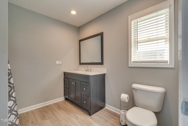 bathroom with hardwood / wood-style flooring, vanity, toilet, and a textured ceiling