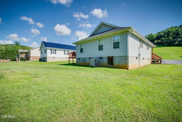 back of house featuring central AC unit and a lawn