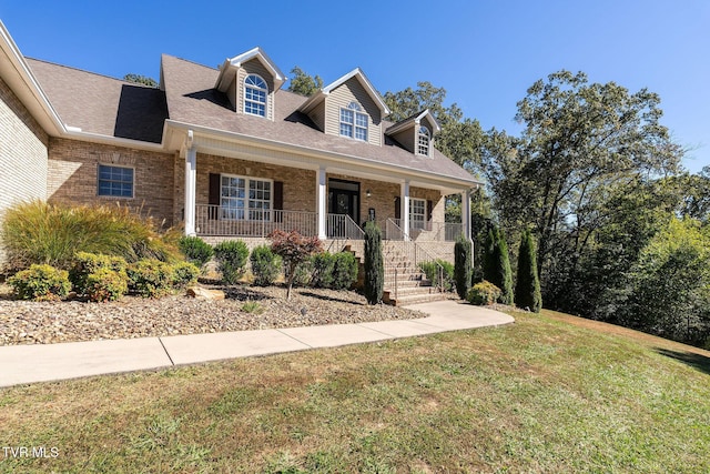 new england style home featuring a porch and a front lawn