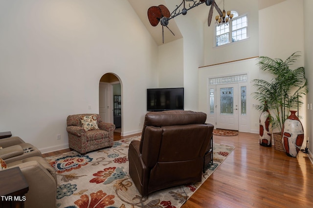 living room with a towering ceiling, hardwood / wood-style flooring, and an inviting chandelier