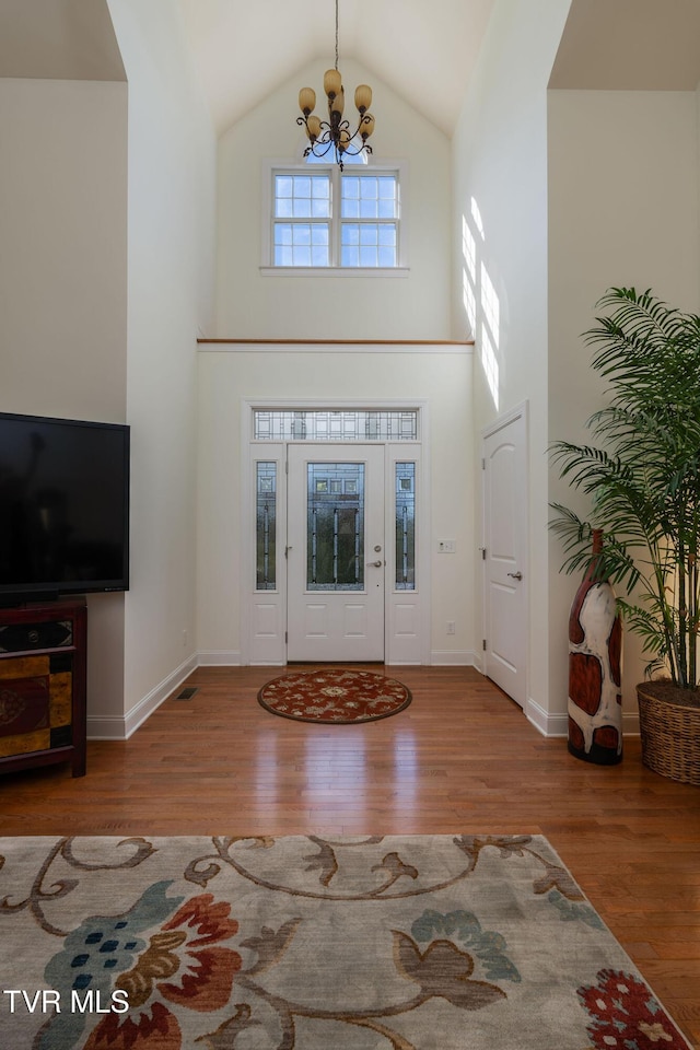 entryway featuring high vaulted ceiling, a chandelier, and light wood-type flooring