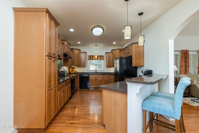 kitchen with black appliances, kitchen peninsula, sink, and hanging light fixtures