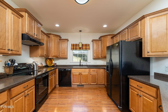 kitchen featuring sink, light hardwood / wood-style flooring, hanging light fixtures, and black appliances