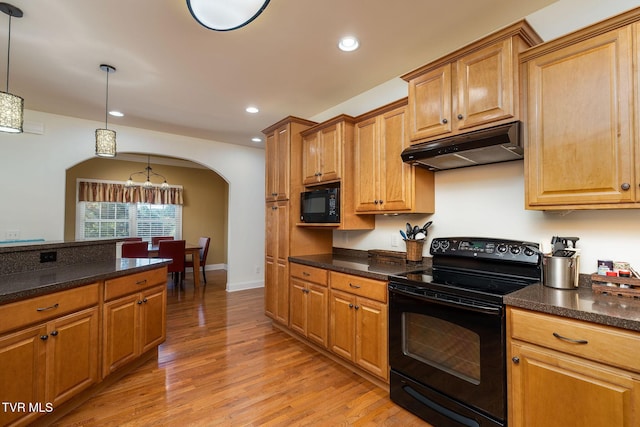 kitchen featuring black appliances, decorative light fixtures, light hardwood / wood-style floors, and dark stone countertops