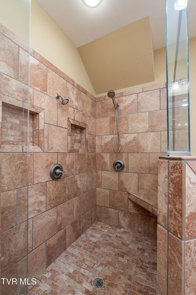 bathroom featuring a tile shower and lofted ceiling