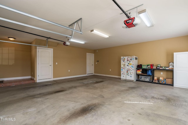 garage featuring white fridge and a garage door opener