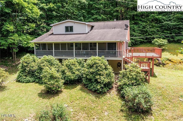 view of front of home featuring a sunroom, a wooden deck, and a front lawn