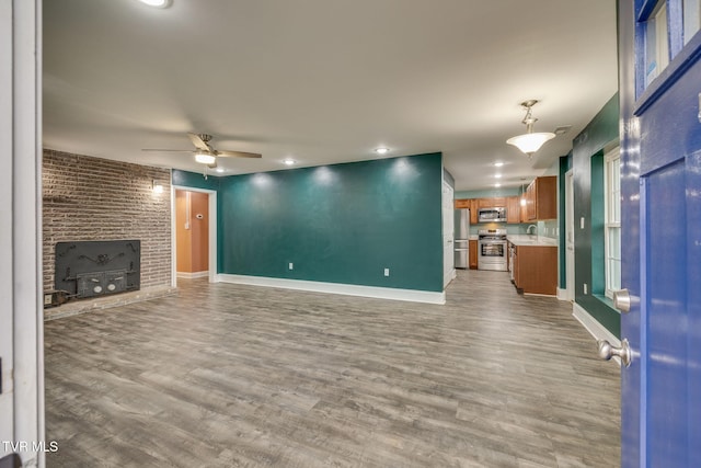 unfurnished living room featuring hardwood / wood-style flooring, ceiling fan, and sink