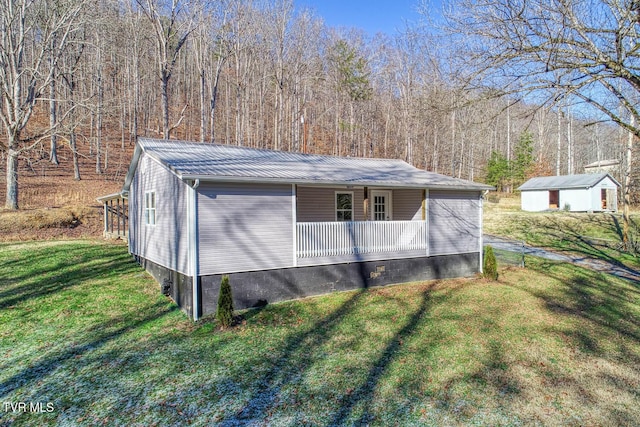 view of home's exterior featuring a porch, a storage shed, and a yard