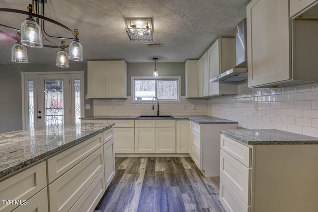 kitchen featuring sink, wall chimney exhaust hood, hanging light fixtures, dark hardwood / wood-style flooring, and white cabinets