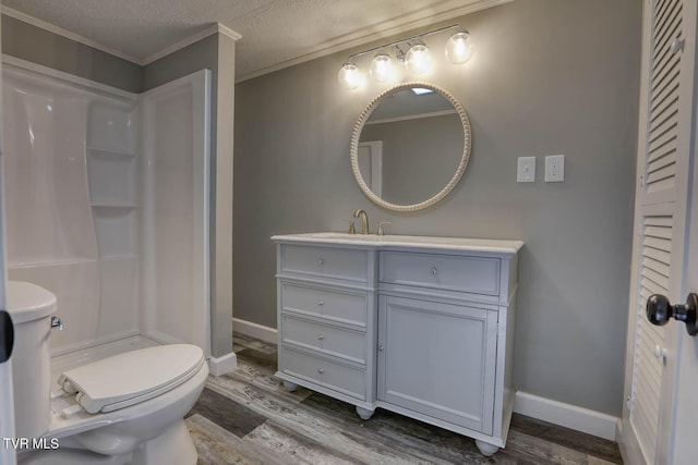 bathroom with vanity, a textured ceiling, crown molding, hardwood / wood-style flooring, and toilet