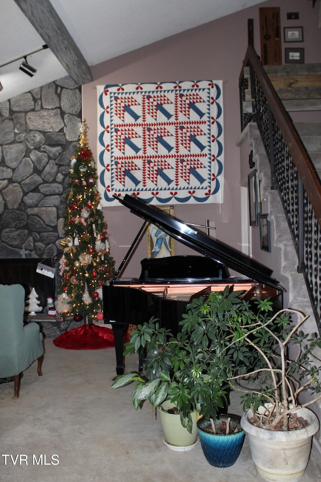 interior space featuring carpet, vaulted ceiling with beams, and a stone fireplace