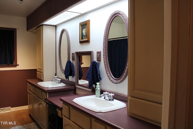 bathroom featuring tile patterned flooring, vanity, and wood walls