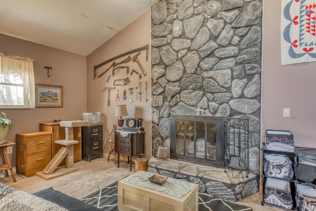 carpeted living area featuring a stone fireplace and a textured ceiling