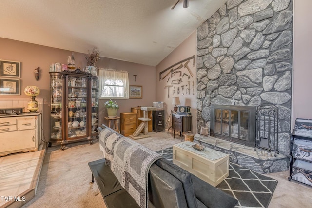 living area featuring carpet flooring, a textured ceiling, a stone fireplace, and vaulted ceiling