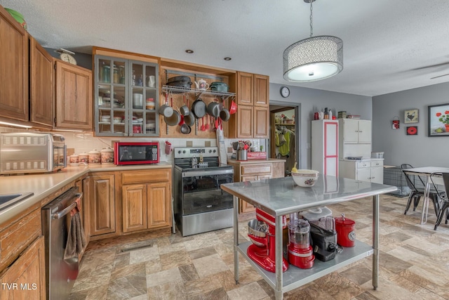kitchen featuring stone finish flooring, pendant lighting, light countertops, brown cabinets, and stainless steel appliances
